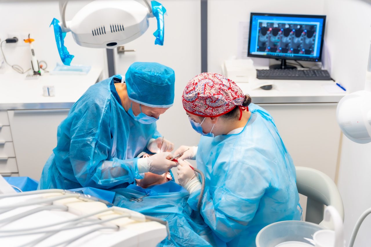 Dentist performing dental implant surgery in sterile environment
